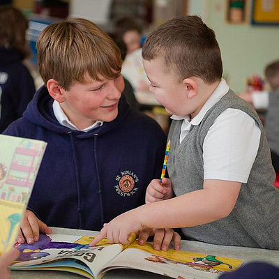 two boys reading a book together in school