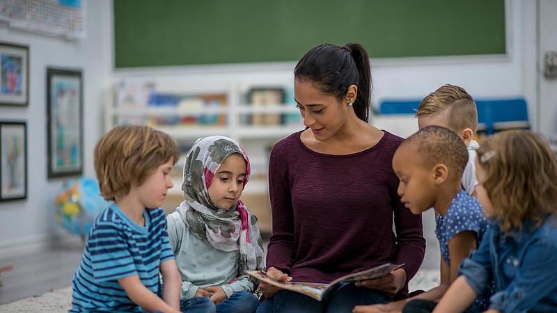 Woman reading a book to a group of children