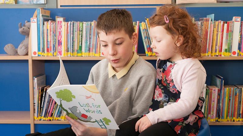 Older boy and younger girl reading a book