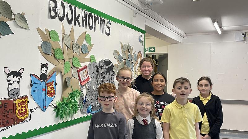 School pupils standing in front of a 'book worms' display