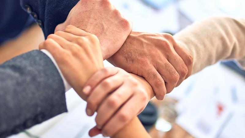 Group of colleagues standing with hands together at the office