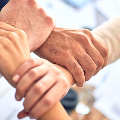 Group of colleagues standing with hands together at the office