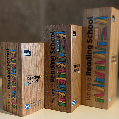 Three wooden Reading Schools trophies, for levels Core, Silver and Gold. 